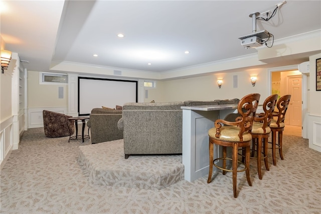 cinema with a decorative wall, crown molding, wainscoting, bar, and light colored carpet