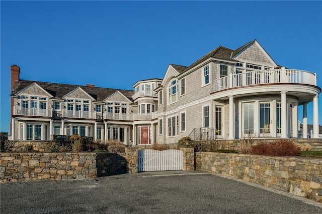 shingle-style home with a balcony and a gate