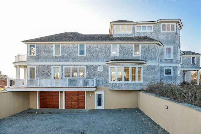 shingle-style home with aphalt driveway, a garage, and a balcony