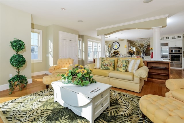 living area with ornate columns, wood finished floors, baseboards, and recessed lighting
