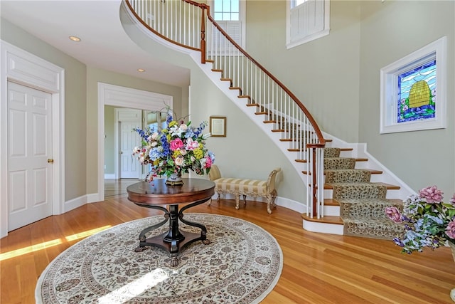 foyer entrance with baseboards, wood finished floors, and stairs