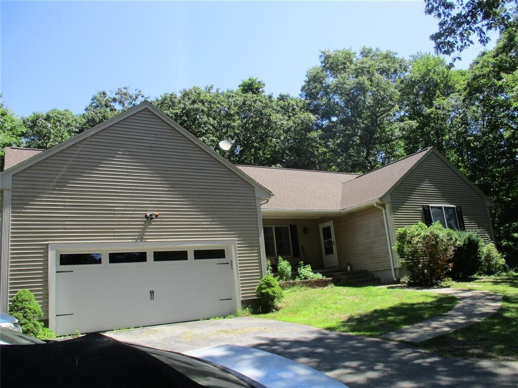 view of front of property with an attached garage, driveway, a front yard, and roof with shingles