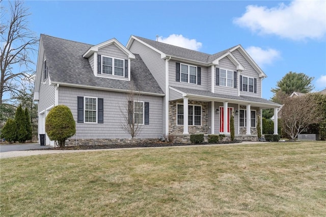 view of front facade with a front lawn, a porch, stone siding, and a shingled roof
