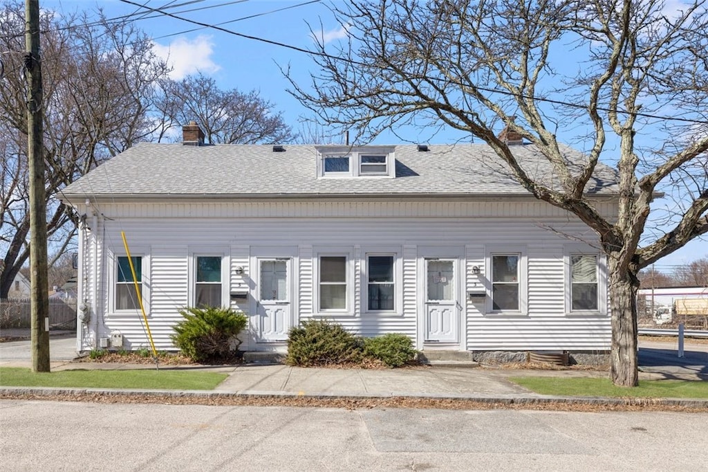 view of front of house with entry steps, roof with shingles, and a chimney