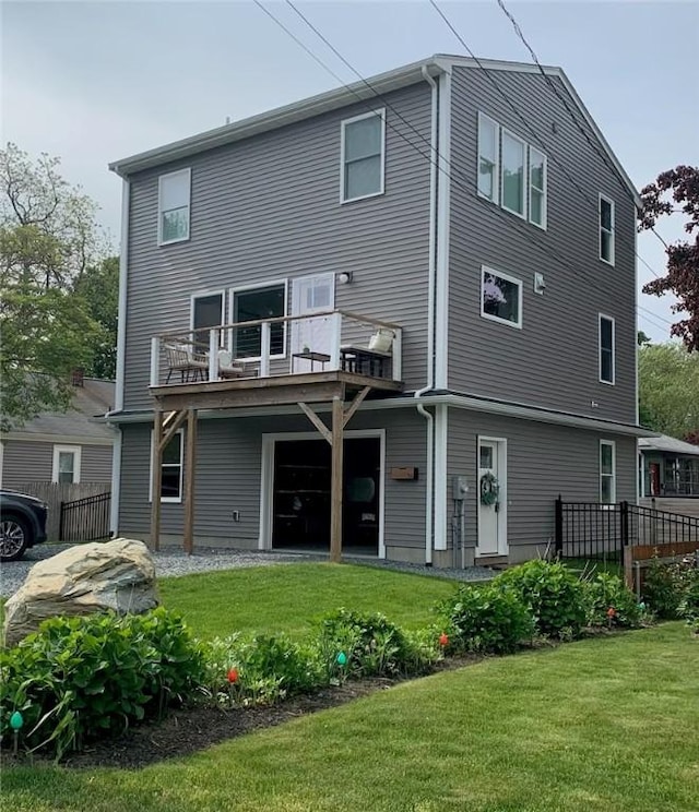 rear view of property featuring fence, a lawn, and a balcony