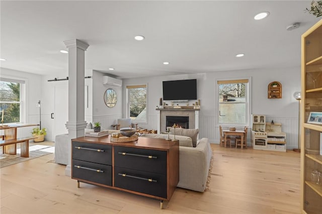 living area featuring a wall mounted air conditioner, a healthy amount of sunlight, and decorative columns