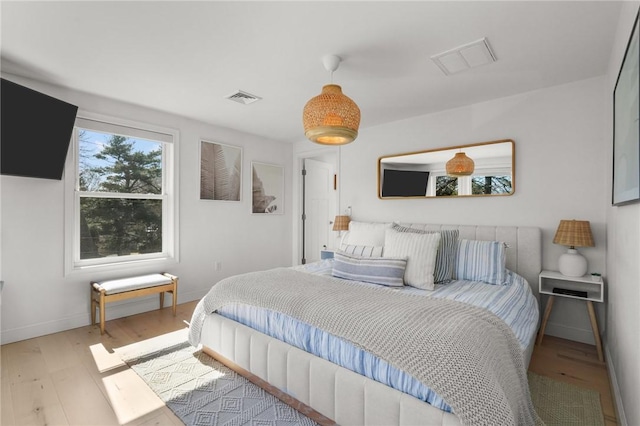 bedroom with baseboards, wood finished floors, and visible vents