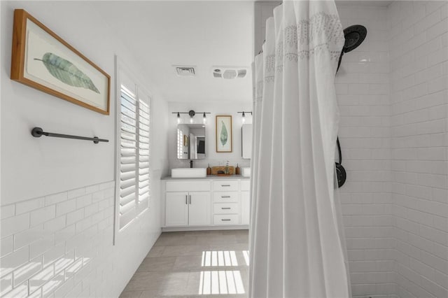 full bath featuring visible vents, a tile shower, and vanity