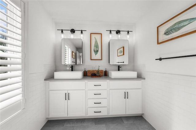 full bath with tile patterned floors, double vanity, a sink, and tile walls