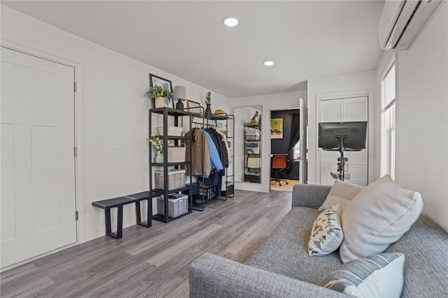 living room with recessed lighting, a wall mounted AC, wood finished floors, and baseboards