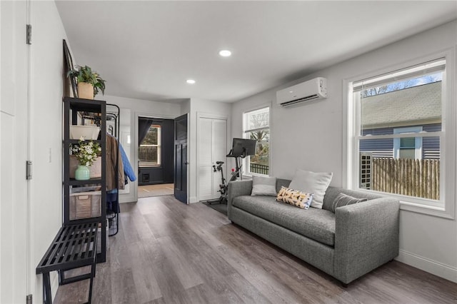 living area featuring recessed lighting, a wall unit AC, wood finished floors, and baseboards
