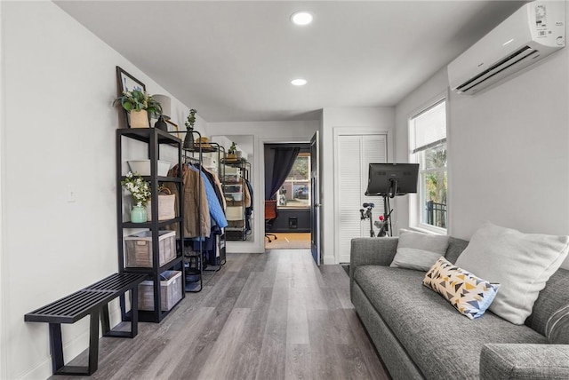 living area featuring wood finished floors, recessed lighting, an AC wall unit, and baseboards
