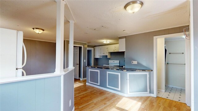 kitchen featuring dark countertops, white appliances, a peninsula, crown molding, and light wood finished floors
