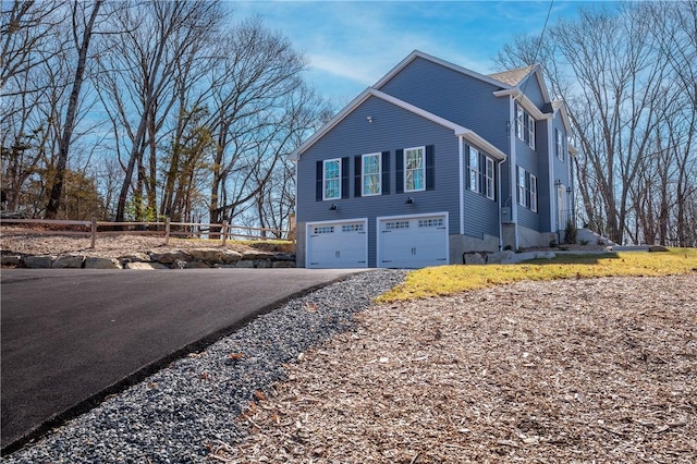 view of home's exterior featuring aphalt driveway, fence, and a garage