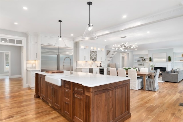 105 Princess Pine Dr, East Greenwich, RI 02818 - kitchen with light wood-style flooring, white cabinetry, built in refrigerator, and a sink