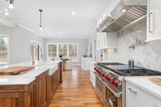 105 Princess Pine Dr, East Greenwich, RI 02818 - kitchen with brown cabinets, ornamental molding, a sink, double oven range, and wall chimney range hood