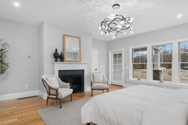 105 Princess Pine Dr, East Greenwich, RI 02818 - bedroom with baseboards, light wood-style flooring, a glass covered fireplace, access to outside, and a notable chandelier