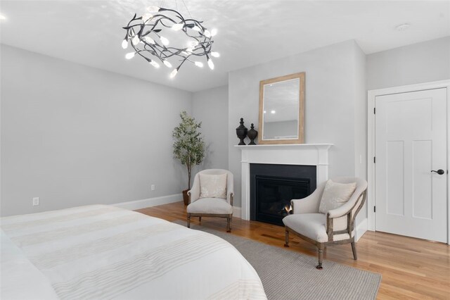 105 Princess Pine Dr, East Greenwich, RI 02818 - bedroom featuring a notable chandelier, a warm lit fireplace, baseboards, and wood finished floors