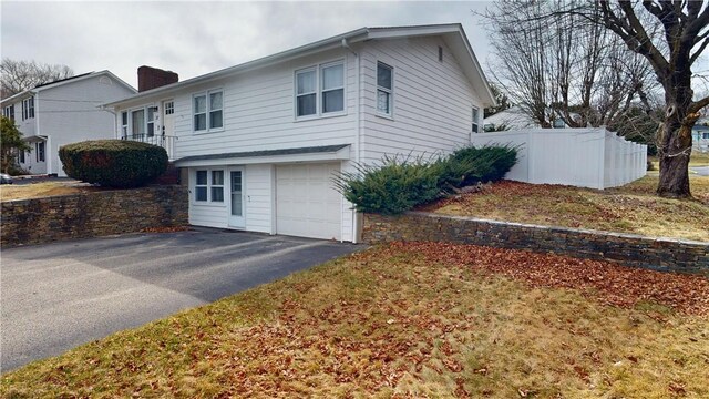 view of front of property with a garage, fence, a chimney, and aphalt driveway