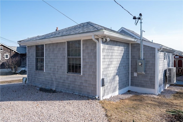 view of side of property featuring a shingled roof and central air condition unit