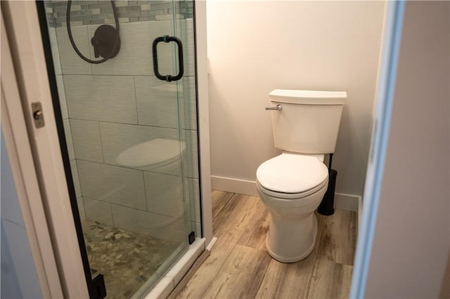full bathroom with baseboards, wood finished floors, toilet, and a stall shower