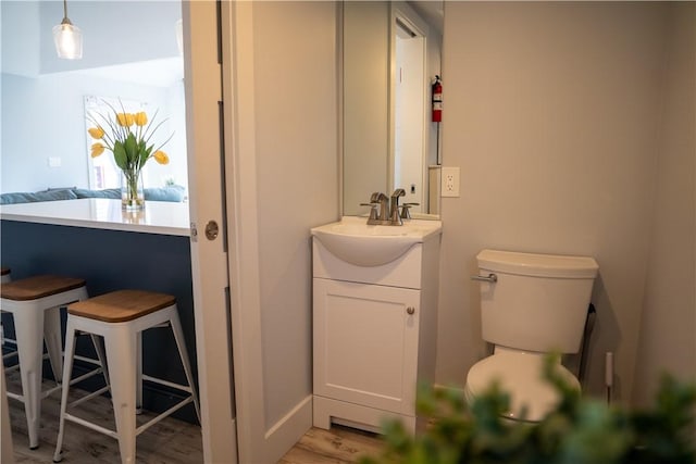 bathroom with toilet, wood finished floors, and vanity