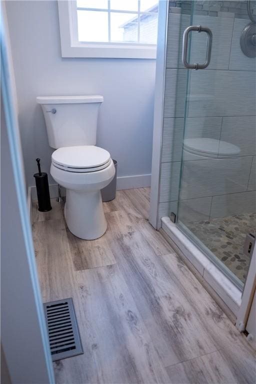 full bathroom with visible vents, a stall shower, baseboards, toilet, and wood finished floors