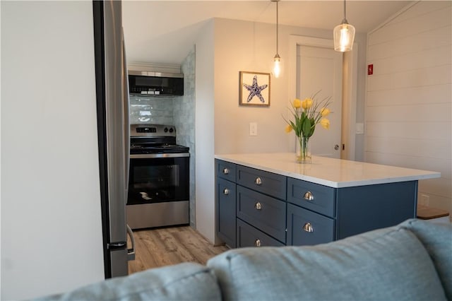 kitchen featuring light wood-style floors, stainless steel appliances, light countertops, decorative light fixtures, and a peninsula