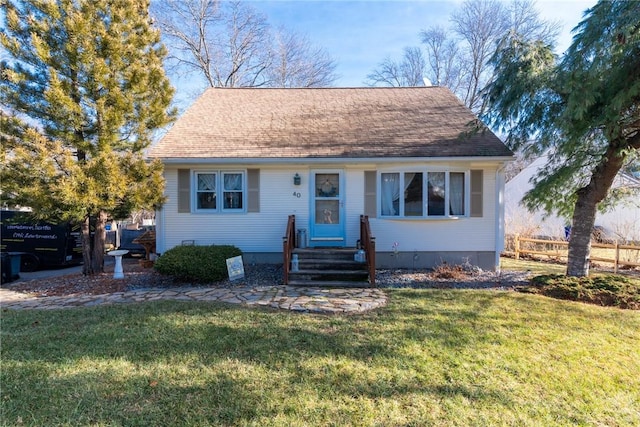 view of front of home with entry steps, a shingled roof, and a front yard