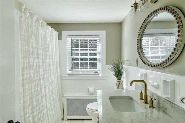 full bath with radiator, toilet, tile walls, and a sink