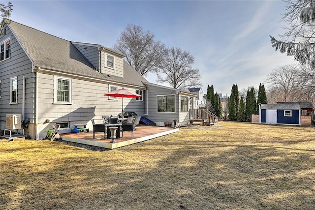 rear view of property featuring a lawn, a shingled roof, an outdoor structure, a shed, and a patio area