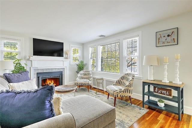 living area with plenty of natural light, wood finished floors, and a tile fireplace