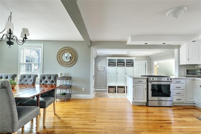 kitchen featuring high end stove, a toaster, beamed ceiling, light wood finished floors, and a notable chandelier