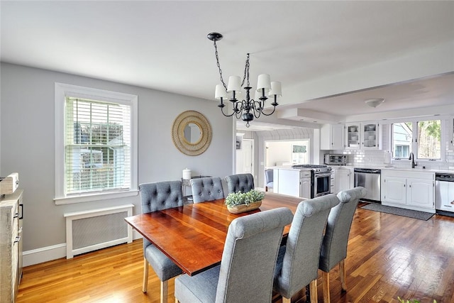 dining room with baseboards, a notable chandelier, light wood-style floors, and radiator heating unit