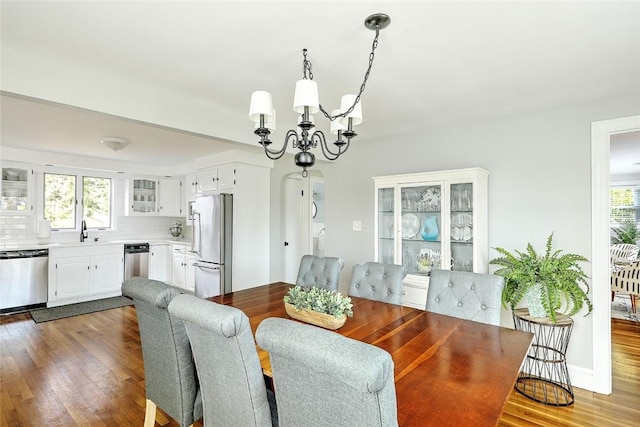 dining space with plenty of natural light, a notable chandelier, and dark wood-style floors