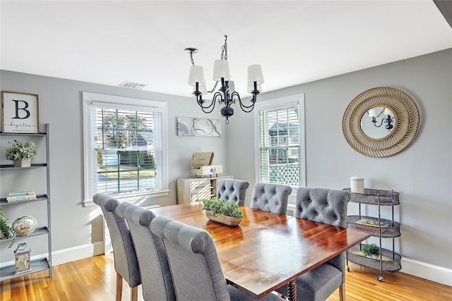 dining area with baseboards, visible vents, light wood-style floors, and an inviting chandelier