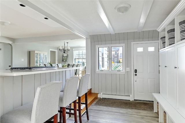 foyer entrance featuring baseboard heating, wooden walls, beamed ceiling, a notable chandelier, and wood finished floors