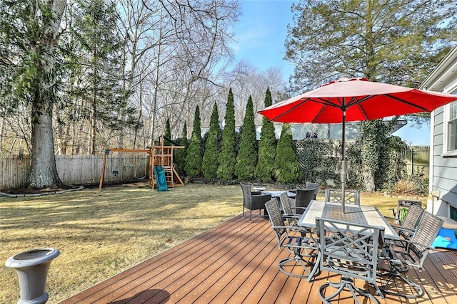 deck featuring a yard, outdoor dining area, fence, and playground community