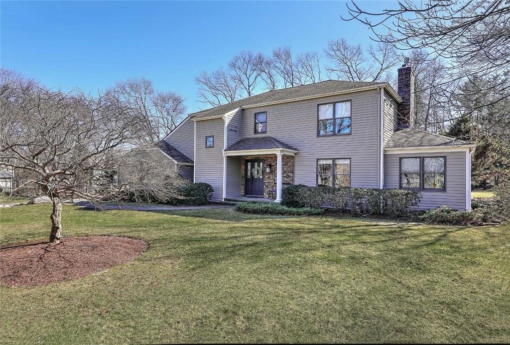 traditional-style home featuring a front lawn and a chimney