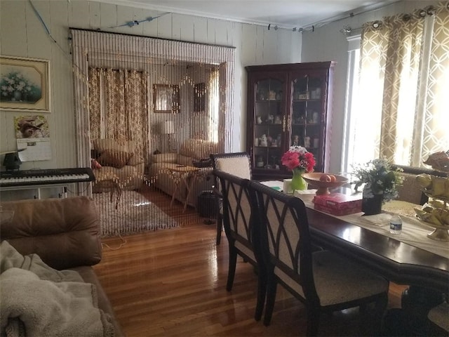 dining space with wood walls, wood finished floors, a wealth of natural light, and ornamental molding