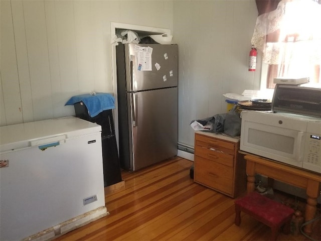 kitchen with light wood-type flooring, freestanding refrigerator, white microwave, and refrigerator