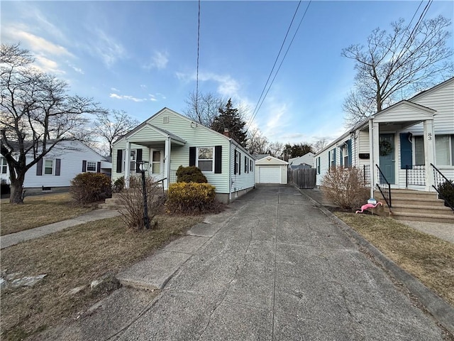 view of front facade with driveway, covered porch, an outbuilding, and a garage