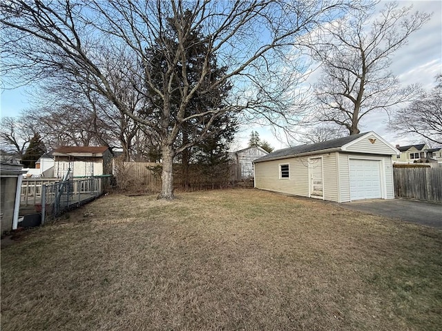 view of yard with driveway, an outbuilding, fence, and a garage