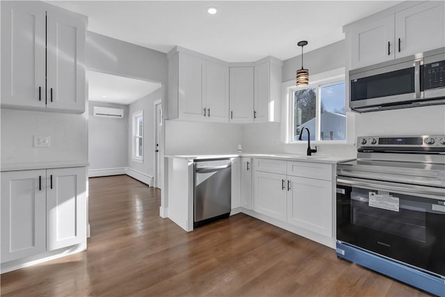 kitchen featuring light countertops, stainless steel appliances, dark wood-type flooring, and a wall mounted air conditioner