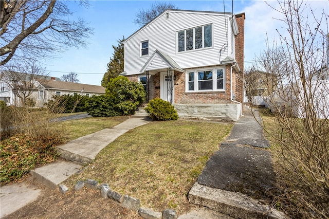 view of front of home with a front lawn, a chimney, and brick siding