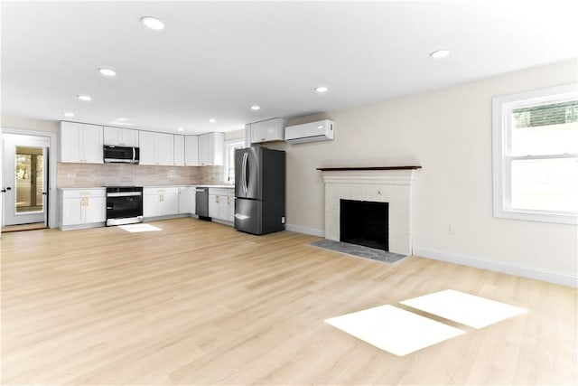 kitchen with light countertops, white cabinetry, a wall mounted air conditioner, stainless steel appliances, and decorative backsplash