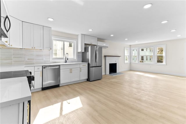 kitchen featuring backsplash, light countertops, appliances with stainless steel finishes, and light wood finished floors