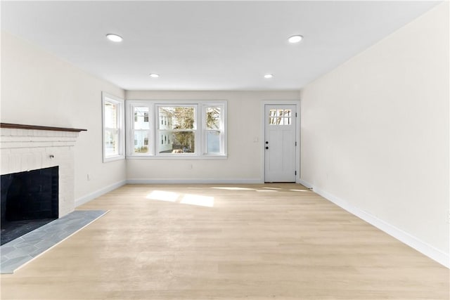unfurnished living room with a healthy amount of sunlight, light wood-type flooring, and a brick fireplace