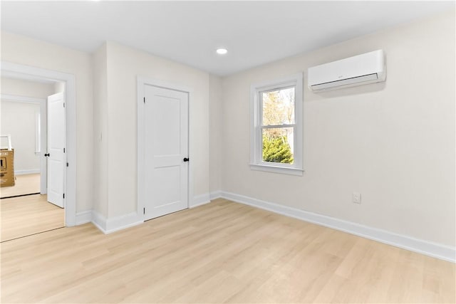 unfurnished room with light wood finished floors, baseboards, a wall unit AC, and recessed lighting