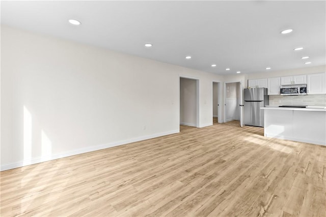 unfurnished living room featuring recessed lighting, baseboards, and light wood-type flooring